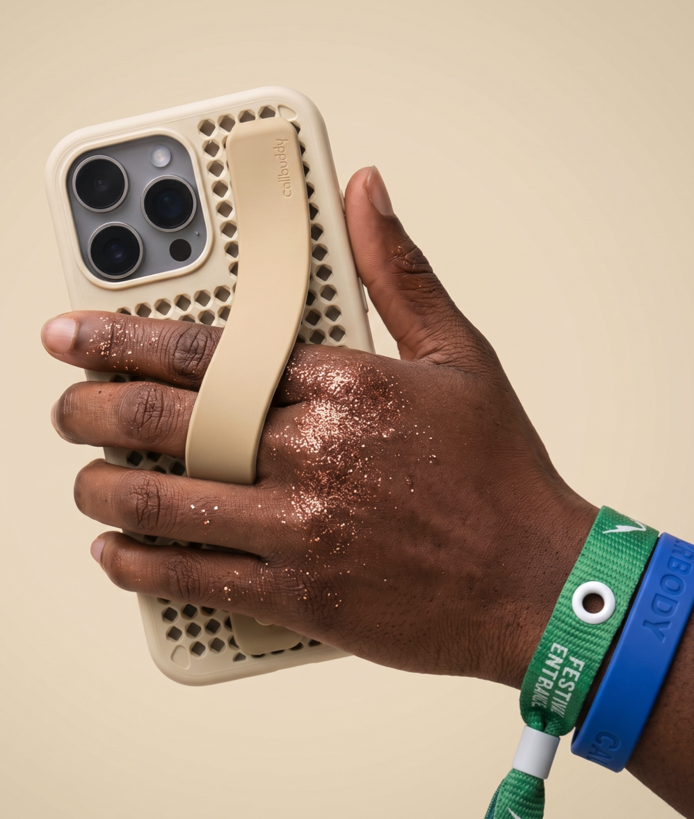 Hand holding the sand perforated phone case with strap and festival wristbands