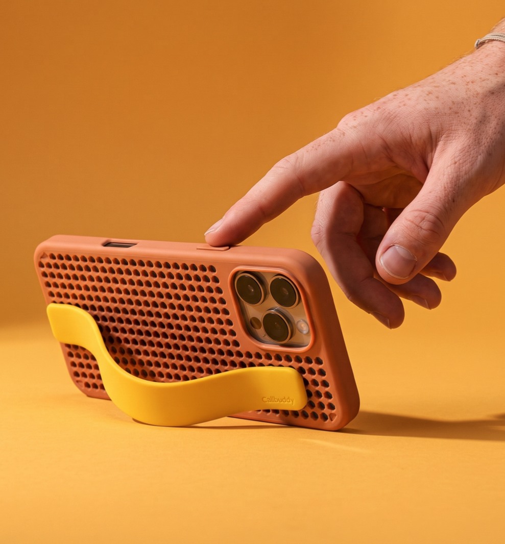 Hand pressing the button on the coral perforated phone case with yellow strap