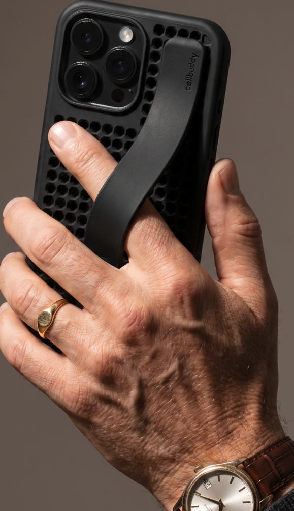 Hand wearing a watch holding the black perforated phone case with strap